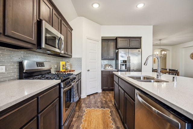 kitchen with sink, an inviting chandelier, stainless steel appliances, light stone countertops, and decorative light fixtures