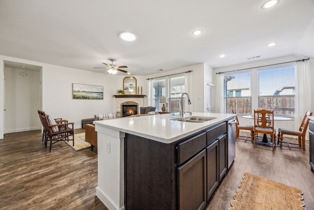 kitchen featuring dark brown cabinetry, dark hardwood / wood-style flooring, sink, and a center island with sink