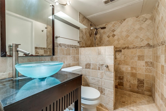 bathroom with tiled shower, toilet, tasteful backsplash, tile walls, and vanity