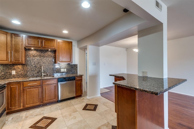 kitchen with sink, a breakfast bar area, appliances with stainless steel finishes, dark stone countertops, and backsplash