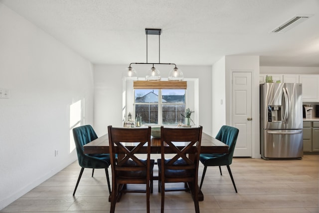 dining space with a textured ceiling and light wood-type flooring