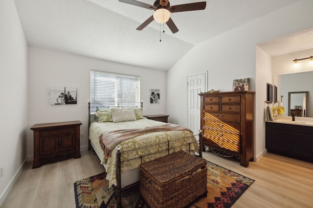 bedroom featuring lofted ceiling, ensuite bathroom, ceiling fan, and light wood-type flooring