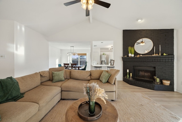 living room featuring ceiling fan, vaulted ceiling with beams, a fireplace, and light hardwood / wood-style flooring