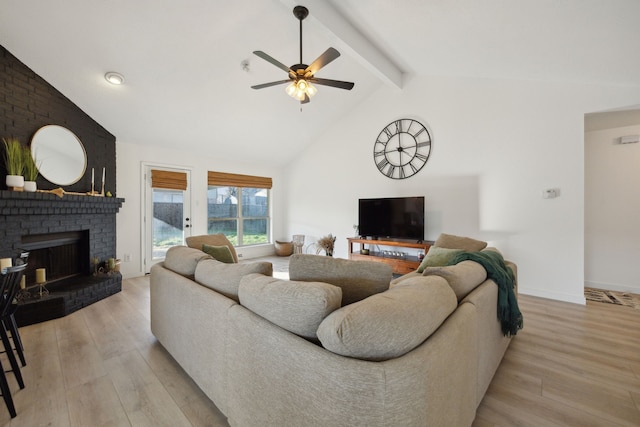 living room with beamed ceiling, ceiling fan, a fireplace, and light hardwood / wood-style flooring