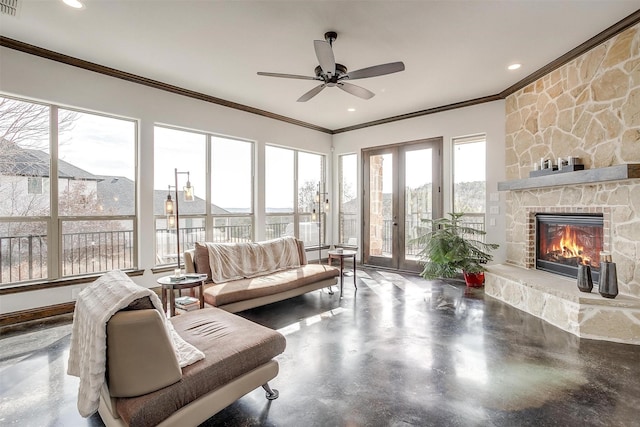 living room with crown molding, a stone fireplace, and concrete floors