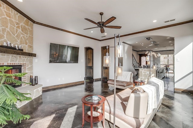 living room with ceiling fan, ornamental molding, and a stone fireplace