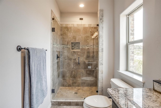 bathroom featuring walk in shower, plenty of natural light, toilet, and vanity