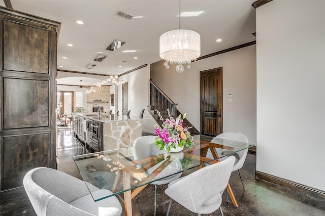 dining space with crown molding, a fireplace, and a chandelier