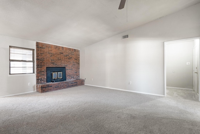 unfurnished living room featuring ceiling fan, a textured ceiling, a brick fireplace, vaulted ceiling, and light colored carpet