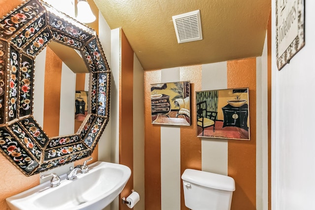 bathroom with sink, a textured ceiling, and toilet