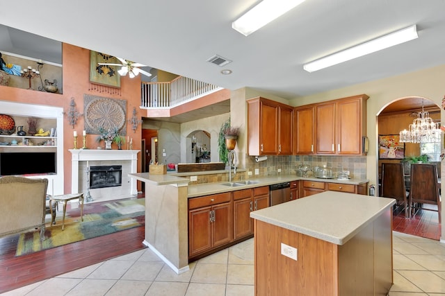 kitchen featuring a center island, sink, light tile patterned floors, and kitchen peninsula