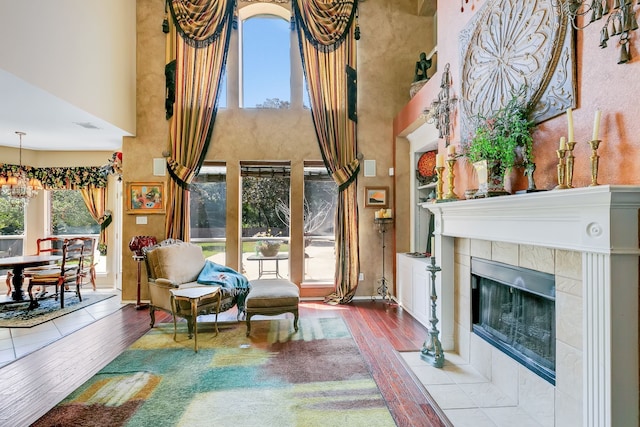 sitting room featuring a towering ceiling, hardwood / wood-style floors, a notable chandelier, and a fireplace