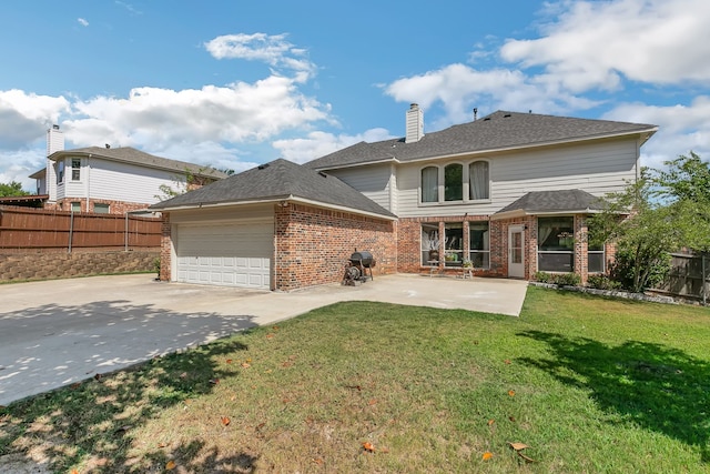 back of property featuring a garage, a lawn, and a patio area