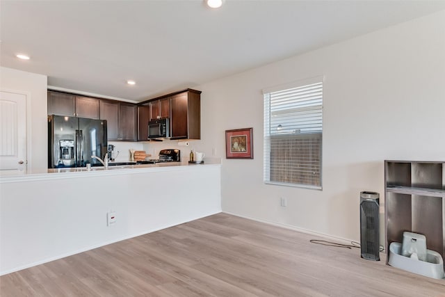 kitchen featuring dark brown cabinetry, sink, light hardwood / wood-style flooring, and black appliances