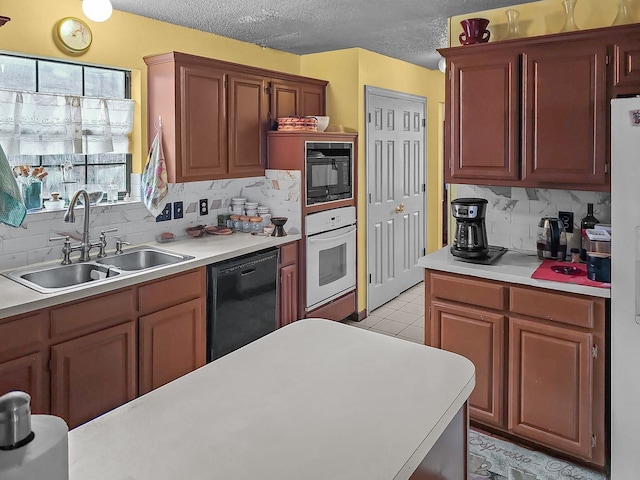 kitchen with sink, light tile patterned floors, backsplash, black appliances, and a textured ceiling