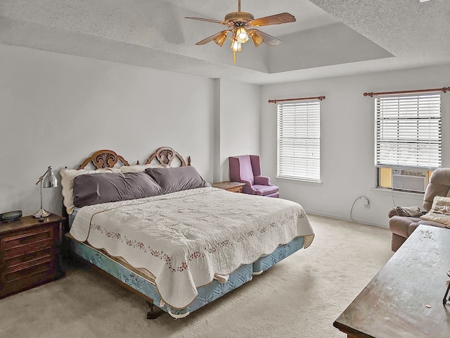 bedroom with carpet floors, cooling unit, ceiling fan, a tray ceiling, and a textured ceiling