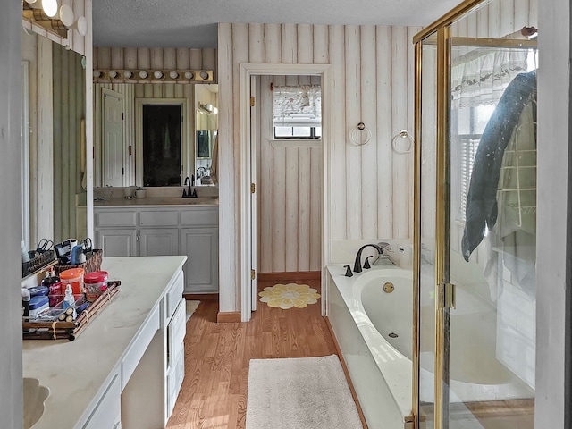 bathroom featuring vanity, wood-type flooring, shower with separate bathtub, and a textured ceiling