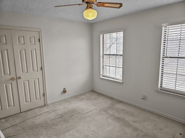 carpeted empty room with ceiling fan and a textured ceiling