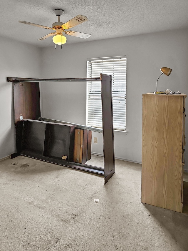 carpeted empty room featuring ceiling fan and a textured ceiling