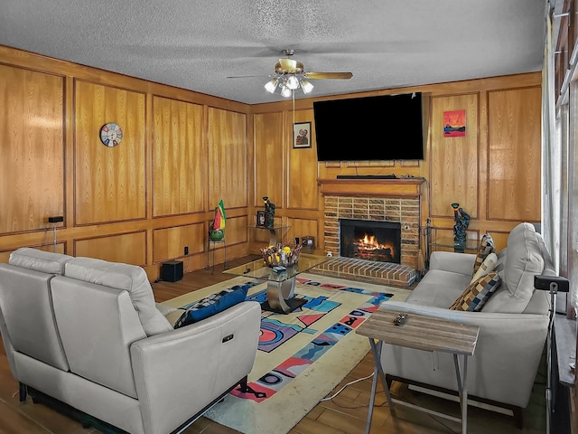 living room featuring a textured ceiling, a fireplace, and ceiling fan