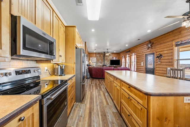 kitchen featuring ceiling fan, appliances with stainless steel finishes, a center island, and light wood-type flooring