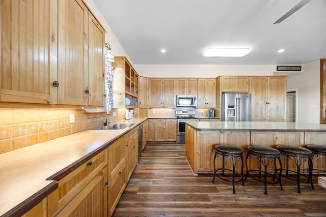 kitchen with sink, a kitchen breakfast bar, decorative backsplash, stainless steel appliances, and dark wood-type flooring