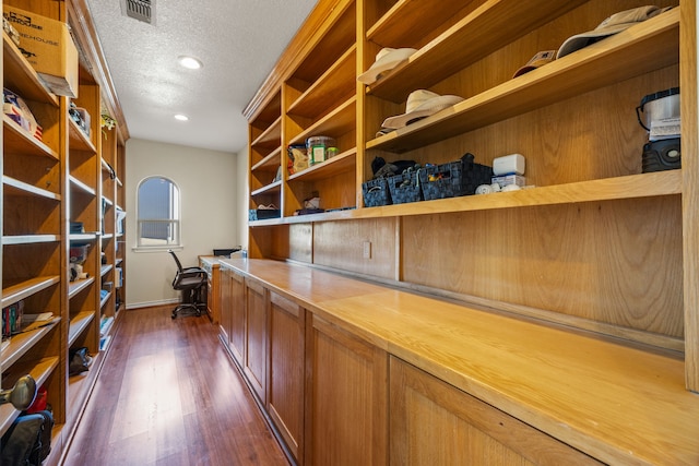 unfurnished office featuring built in desk, dark hardwood / wood-style floors, and a textured ceiling