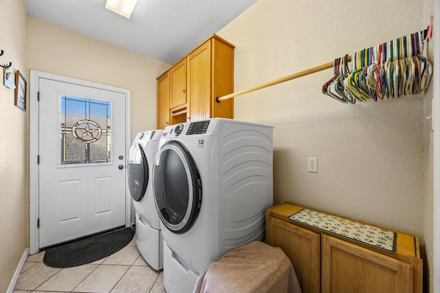 clothes washing area with cabinets, washing machine and dryer, and light tile patterned floors