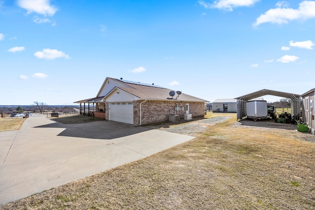 view of side of property with a garage, cooling unit, a carport, and a lawn