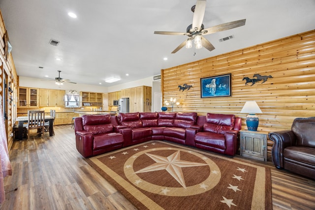 living room with sink, log walls, dark hardwood / wood-style floors, and ceiling fan