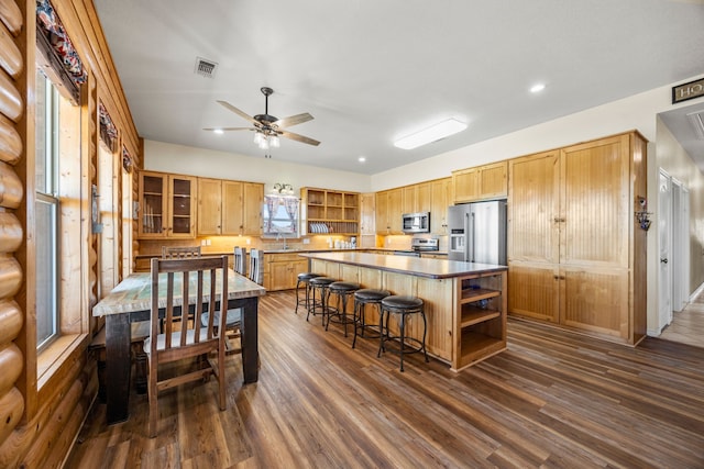 kitchen featuring appliances with stainless steel finishes, a breakfast bar, sink, dark hardwood / wood-style flooring, and a center island