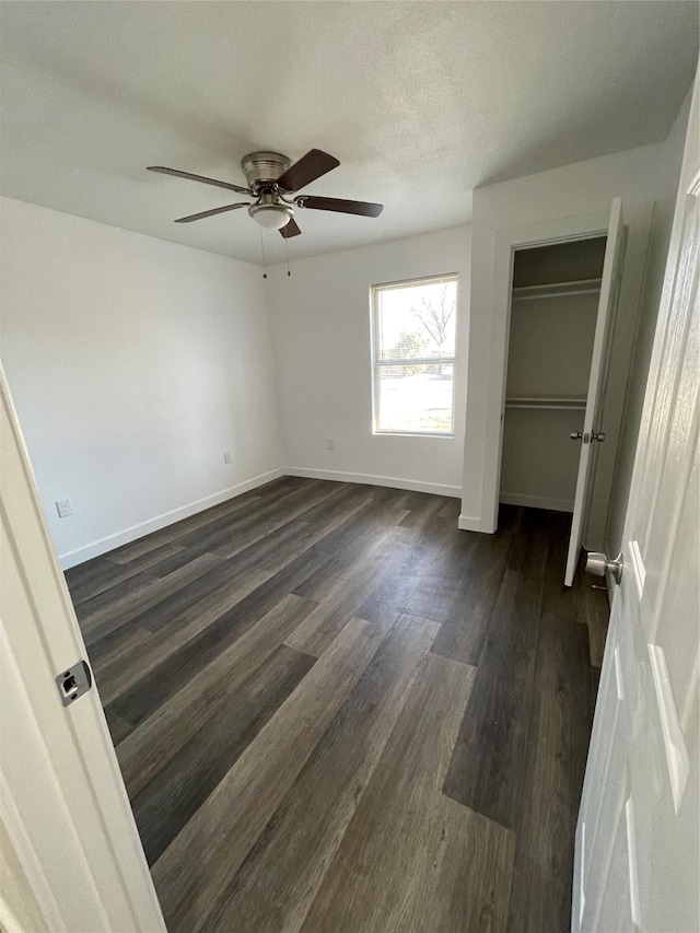 unfurnished bedroom featuring dark hardwood / wood-style floors, a textured ceiling, ceiling fan, and a closet