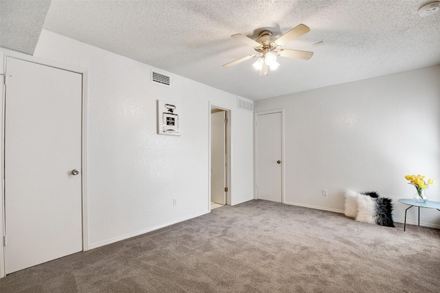 unfurnished room with ceiling fan, carpet floors, and a textured ceiling