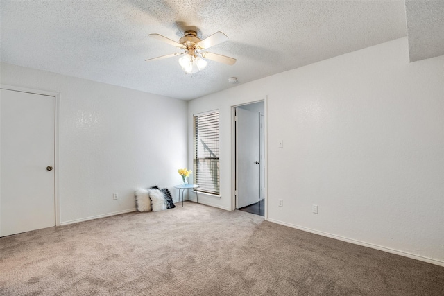 carpeted spare room featuring a textured ceiling and ceiling fan