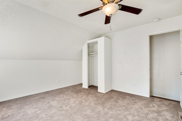 unfurnished bedroom with lofted ceiling, ceiling fan, light carpet, a textured ceiling, and a closet