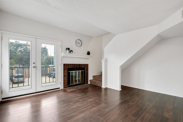 unfurnished living room with dark hardwood / wood-style flooring, a brick fireplace, french doors, and a textured ceiling