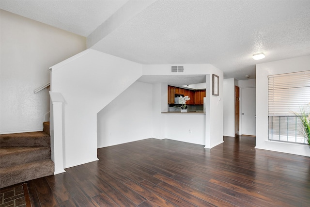 unfurnished living room featuring dark hardwood / wood-style flooring and a textured ceiling