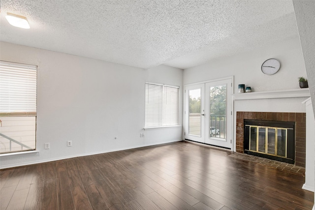 unfurnished living room featuring a brick fireplace, dark wood-type flooring, and a textured ceiling