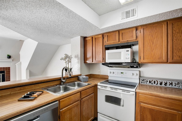 kitchen with sink, white appliances, vaulted ceiling, and a textured ceiling