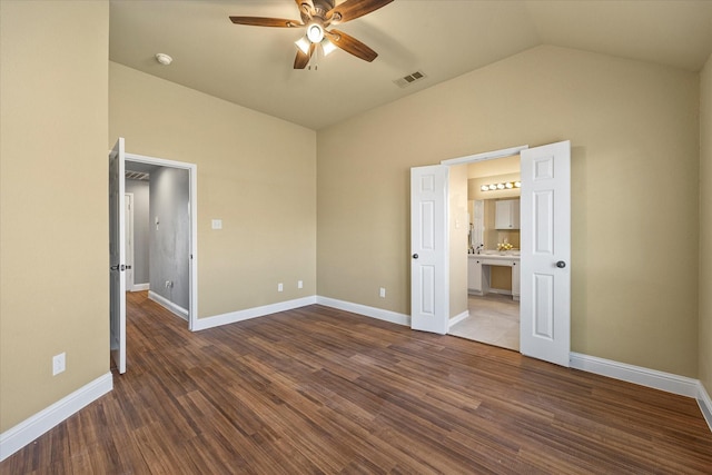 unfurnished bedroom with vaulted ceiling, dark hardwood / wood-style floors, ceiling fan, and ensuite bath