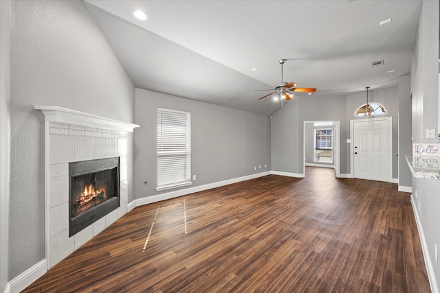 unfurnished living room featuring a tiled fireplace, lofted ceiling, dark hardwood / wood-style floors, and ceiling fan