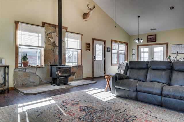 living room with french doors, dark hardwood / wood-style floors, high vaulted ceiling, and a wood stove