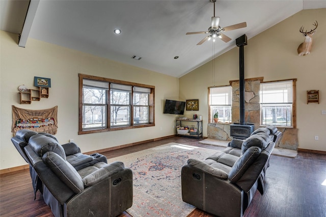 living room with ceiling fan, high vaulted ceiling, a wood stove, and dark hardwood / wood-style floors