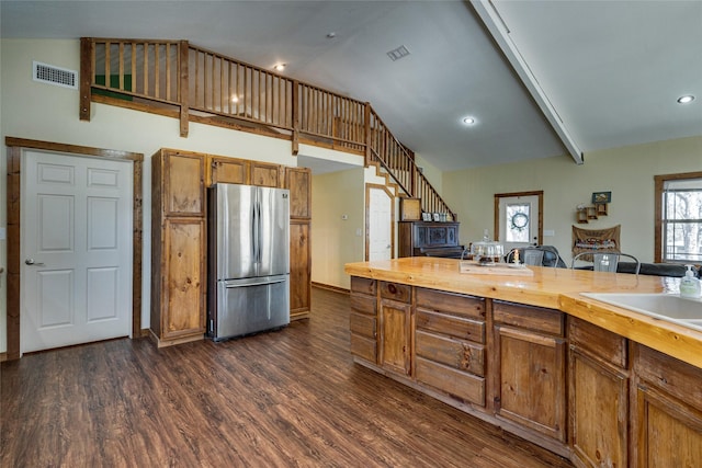 kitchen with lofted ceiling, sink, wooden counters, stainless steel fridge, and dark hardwood / wood-style flooring