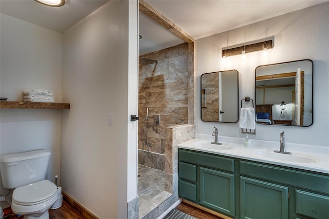 bathroom featuring a tile shower, vanity, hardwood / wood-style flooring, and toilet