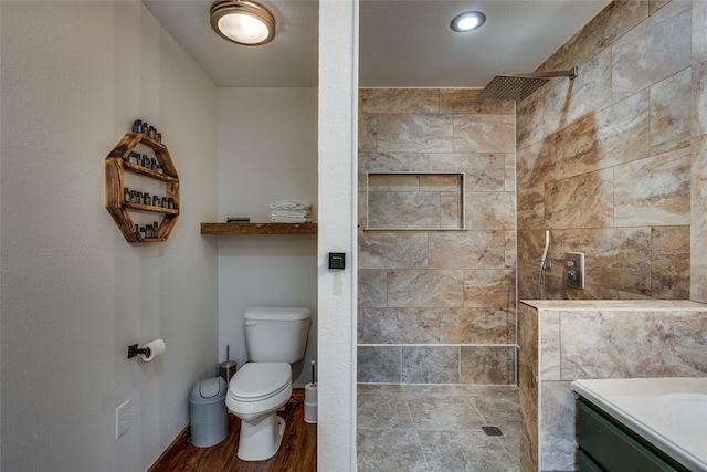 bathroom featuring vanity, toilet, and a tile shower