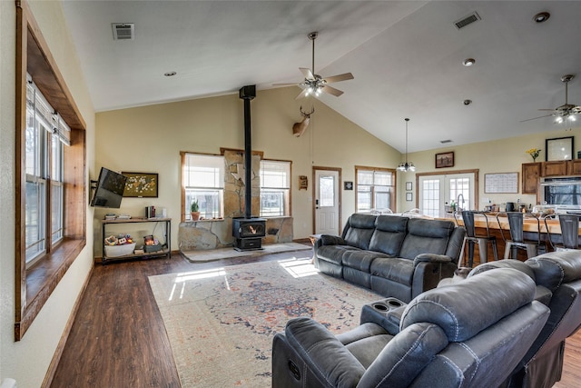 living room featuring ceiling fan, high vaulted ceiling, a wood stove, and dark hardwood / wood-style flooring