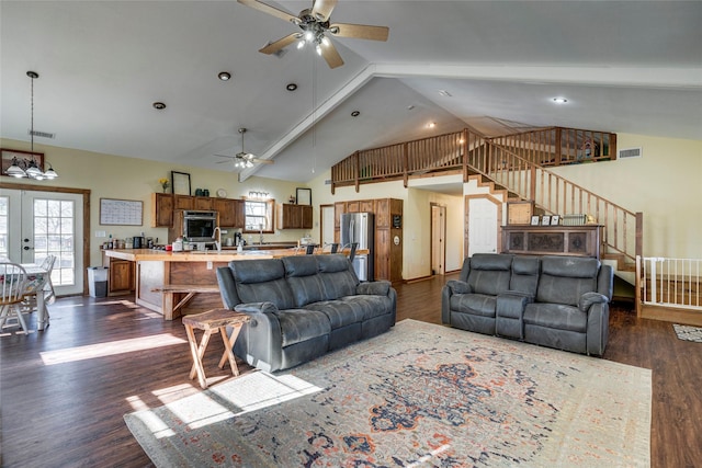 living room with dark wood-type flooring, ceiling fan with notable chandelier, high vaulted ceiling, and french doors