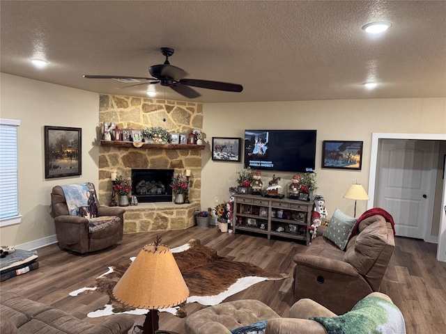 living room with ceiling fan, hardwood / wood-style floors, a textured ceiling, and a fireplace