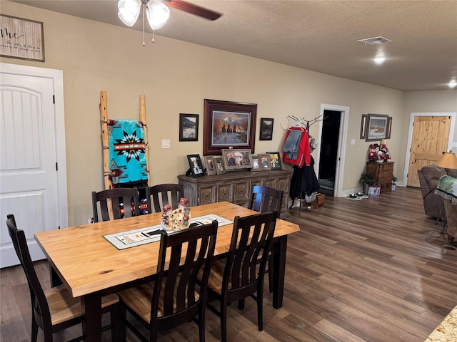 dining area with dark wood-type flooring, ceiling fan, and a textured ceiling